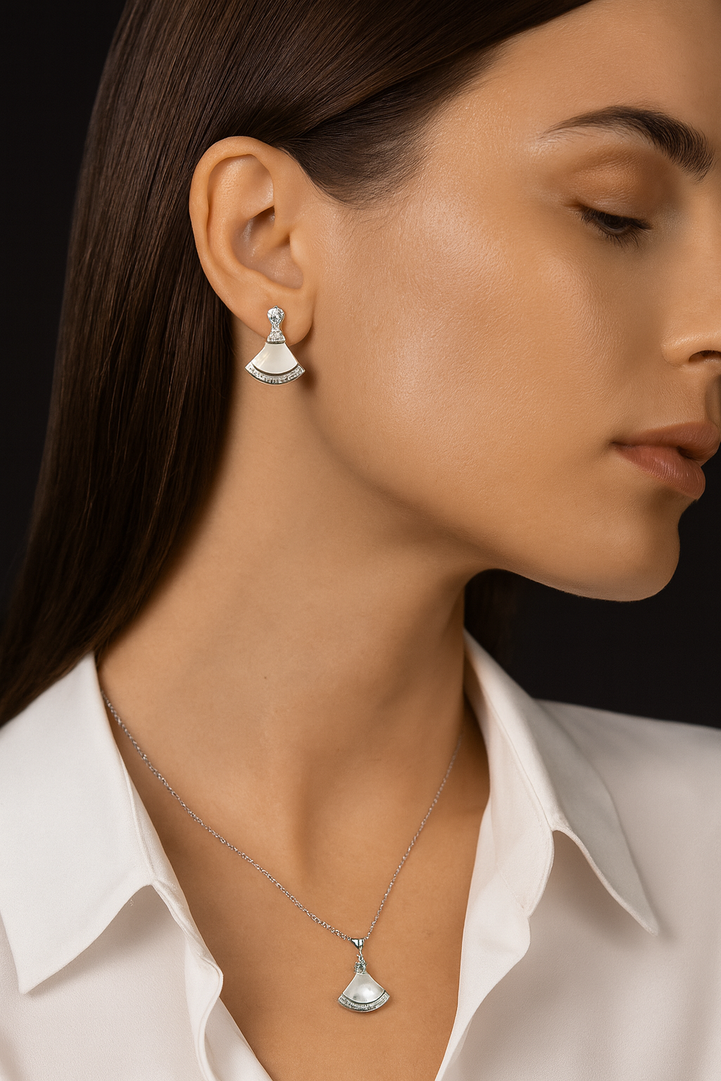 Woman wearing silver earrings and necklace against a neutral background
