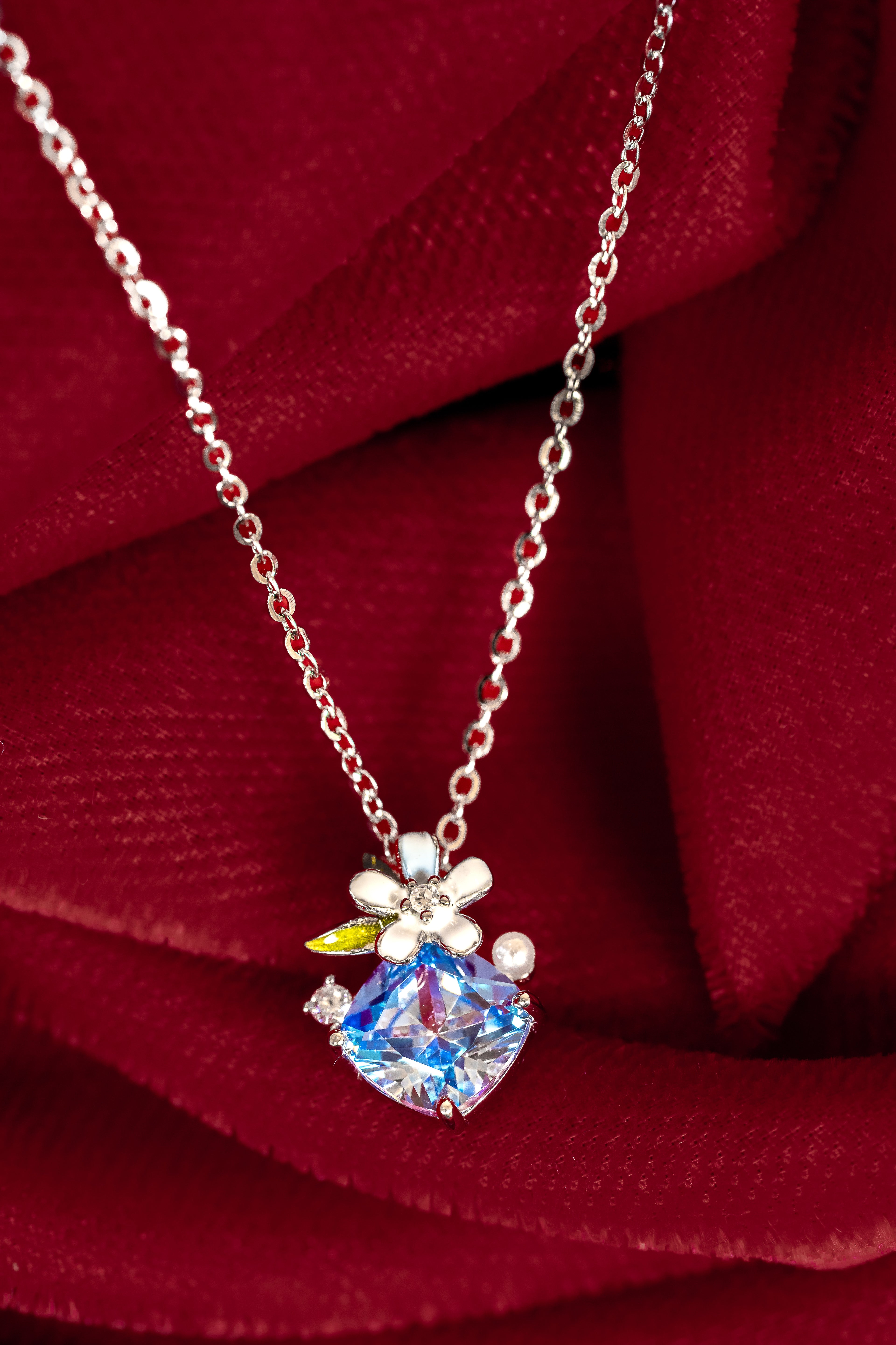 Necklace with a blue gemstone pendant on a red fabric background